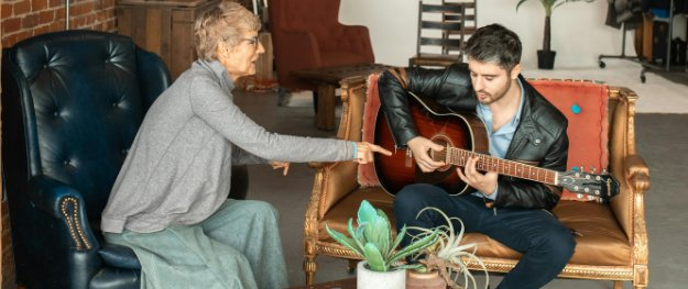 A guitar teacher and student playing side by side